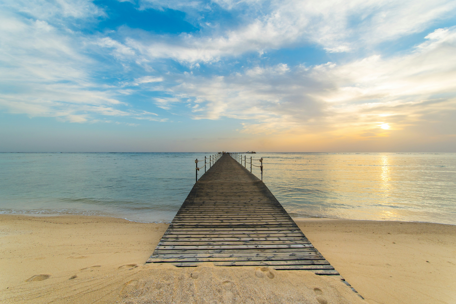 Long wooden pier reaching into calm turquoise Red Sea water at dawn