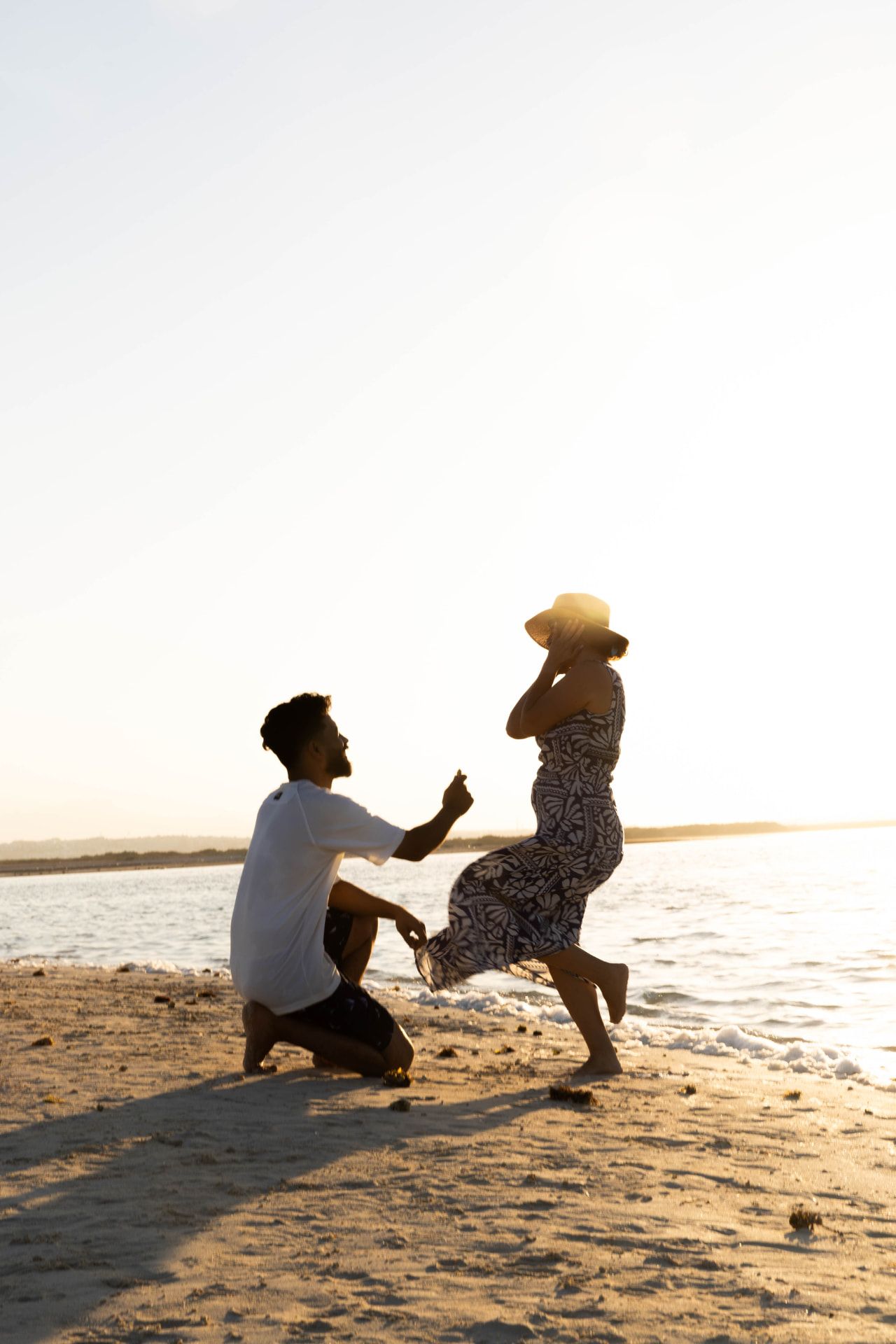 A marriage proposal in silhouette on a quiet Red Sea beach at sunset