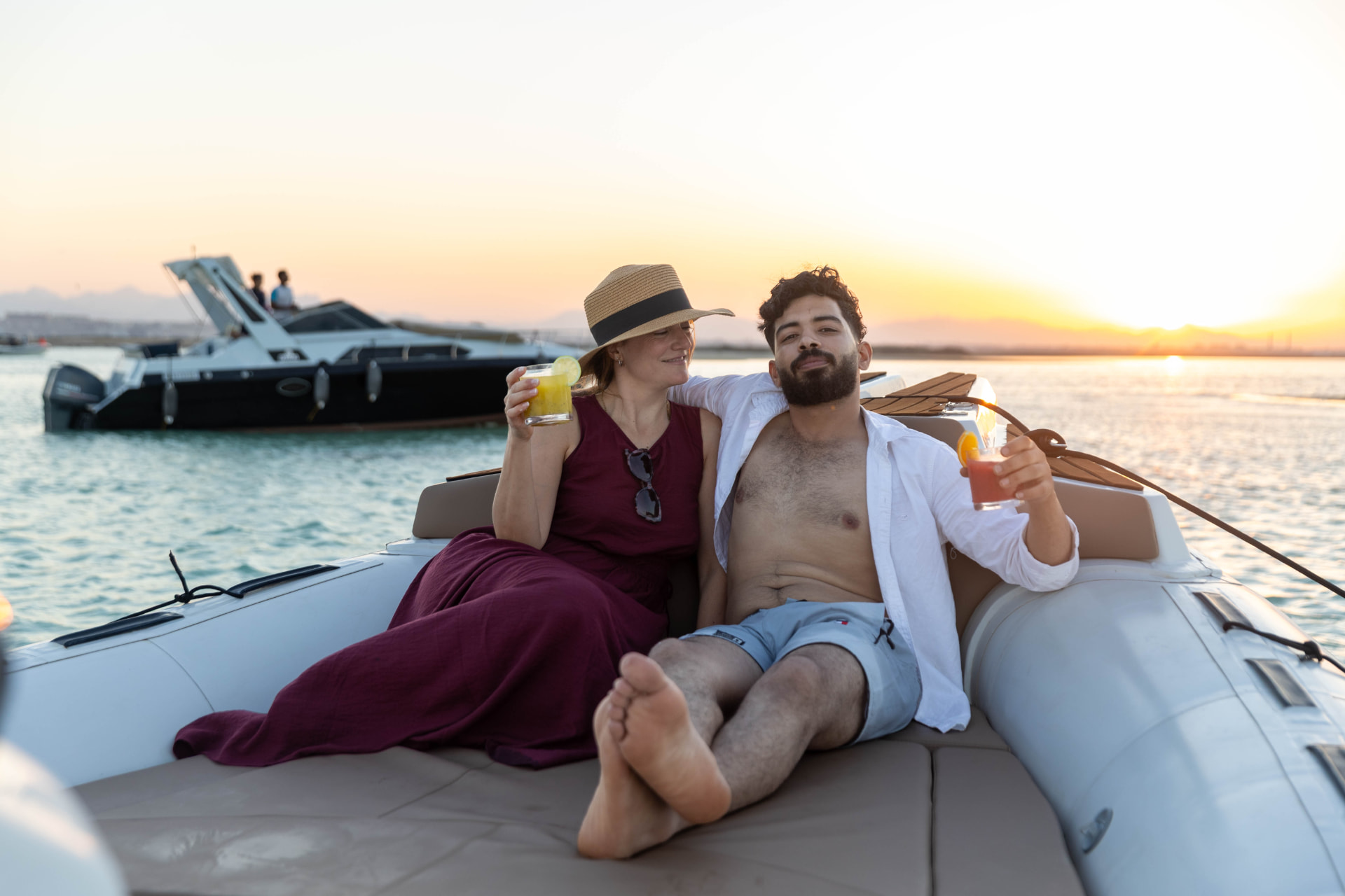 Couple relaxing with drinks on the bow of the Maro Redsea speedboat at sunset off Hurghada