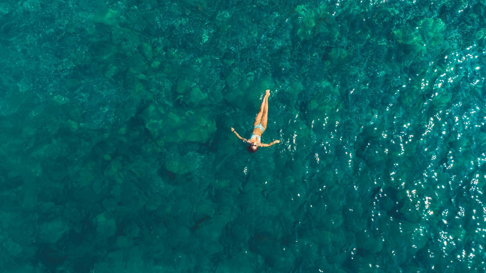 Aerial view of turquoise Red Sea water near Hurghada with a guest swimming in the shallows