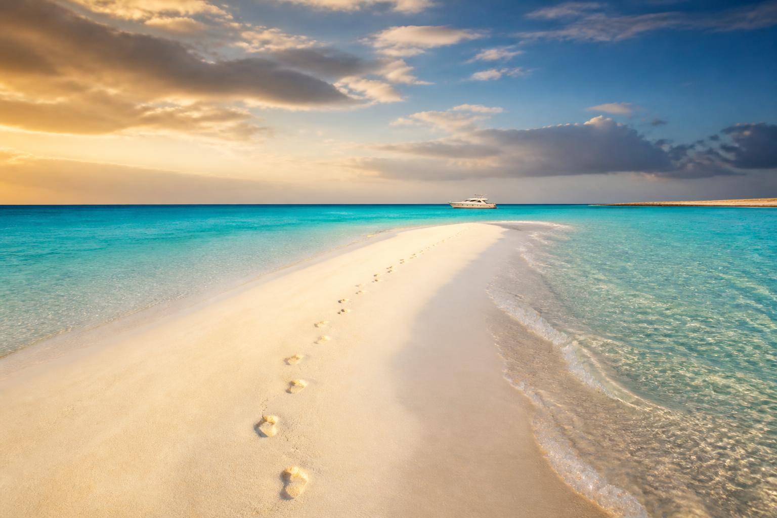 Long white sandbank with turquoise Red Sea water on both sides and the Maro speedboat in the background
